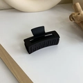 Gros plan sur la pince à cheveux géométrique noire mate sur un fond crème minimaliste - Style Rectangle (18076)