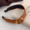 Détail d'un serre-tête marron texturé avec ornement ambré posé sur un livre - Décor Marbre Brun (27358D)