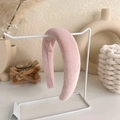 Detail of soft pink plush wide headband on display stand with cozy decorative background - Pink Plush Style