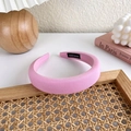 Detailansicht eines gepolsterten rosa Haarreifens mit handgemachtem Etikett und Textur - Rosa