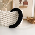 Detail of a black plush fleece headband showing the soft lamb wool texture on a woven basket - Black Sherpa (19539E)