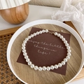 Detail of high-luster white pearls necklace with gold lobster clasp and adjustable chain - 12mm