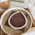 Detailed view of glossy white pearls on a necklace with adjustable golden lobster clasp - 14mm