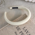 Close-up of beige knitted headband with a textured weave and a handmade woven label - Knitted Woven Style (26004A)