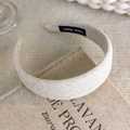 Close-up of a cream fabric headband with a black Hand Made label on its inner surface - Light Beige Fabric Style (26495A)