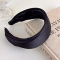 Detail of a padded black satin headband with silk luster placed on a vintage book - Black Thick Padded Satin (27515D)