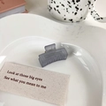 Primer plano de una pinza para el cabello rectangular gris mate en un plato de cerámica - Gris