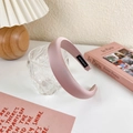 Detalle de diadema acolchada rosa con etiqueta hecha a mano sobre fondo de lámpara crema - Estilo Satén Mate (20118B)