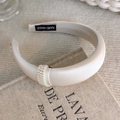 Detail view of cream-colored satin padded headband with pearl ring embellishment - High Top Satin Style (25861A)