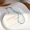 Dettaglio della collana di perline di cristallo blu e bianco su un vassoio decorativo in ceramica - Collana Blu