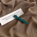 Detail view of wavy dark green matte hair clip on premium brown satin fabric background - Dark Green