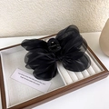 Dettaglio dell'elegante molletta per capelli con fiocco in rete nera su vassoio gioielli - B Nero
