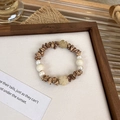 Detaillierte Nahaufnahme von Holzperlenarmband mit Barockperlen und Blumenanhängern - Perlenblume