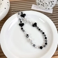 Detail of black heart and white pearl beads phone strap on a minimal ceramic plate - Pearl Heart (21830)
