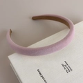 Detalle de diadema de terciopelo rosa con forro antideslizante sobre libro decorativo - Rosa