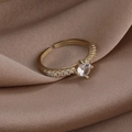 Makroaufnahme eines goldenen Rings mit großem Zirkon und seitlichen Mikro-Zirkonia auf Seide - 1# Runder Zirkonia Vier Krappen