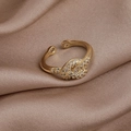 Primer plano de un anillo de nudo dorado con circonitas brillantes sobre satén champán - Estilo Nudo con Strass (5# 15642B)