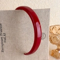 Detail view of the glossy red vintage headband resting on a decorative book background - Red Glossy Lacquered Style (12# 24593)
