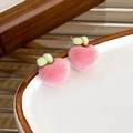 Detailed close-up of pink flocked peach stud earrings with green leaves and metal pins - Red Apple