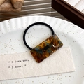 Detailed close-up of tortoise shell pattern acrylic hair tie with gold handmade lettering - Multi-color Orange Hair Tie