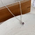 Detailaufnahme einer silbernen O-Kette mit lila herzförmigem Zirkonia-Anhänger im Fokus - C Lila Zirkonia