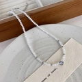 Detail van gefacetteerde kristallen kralenketting met hartvormige hanger op keramische schaal - Wit