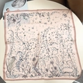 Flat lay of pink silk scarf with floral botanical prints and brown border on a round table - 53x53 / Pink Lily of the Valley