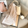 Détail d'un foulard en soie champagne élégant drapé sur un sac à main beige - 65*65 / Kaki