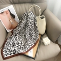 Close-up of leopard print silk scarf tied on a beige bucket bag with satin edges - Brown