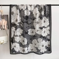 Zwart-witte sjaal met bloemenprint en elegante brede rand aan een metalen kledinghanger - Zwart