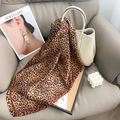 Dettaglio di un foulard in raso con stampa leopardata e bordo marrone su divano in pelle - Stile Quadrato Giallo / Leopardo Giallo