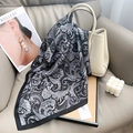 Classic black and white paisley silk scarf displayed on a luxury leather sofa - 65x65 / Black