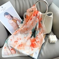 Artistic floral printed silk scarf with vibrant orange and green patterns on handbag - Orange