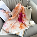 Floral print silk scarf styled on beige handbag with elegant fashion lifestyle aesthetic - Purple