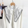 Close-up of black and white polka dot silk scarf with striped edges on wooden hanger - White