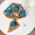 Detail van zijdeachtige sjaal met blauw bloemenpatroon en oranje randen op tafel - Blauw & Oranje Bloemenpatroon