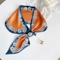 Detailopname van de oranje satijnen sjaal met bloemenmotief en het wasvoorschrift-label - Geel Bloemen