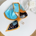 Dettaglio del foulard in seta azzurro e arancione annodato a fiocco su un espositore bianco - Blu Autunno - Blu / 15*75cm