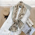 Close-up of silk neck scarf with stripes and pearl chain on a white blazer lapel - Green