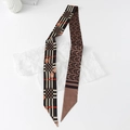 Macro detail of silk-like Twilly scarf with geometric patterns and horse buckle design - Geometric - Brown