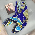 Royal blue silk scarf with baroque chain patterns and bird prints on a grey leather stool - Deep Sea Blue