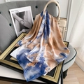 Artistic tie-dye silk-feel scarf draped over a handbag in a stylish interior setting - Blue