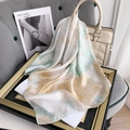 Detail of silk-feel scarf with artistic print draped over a stylish cream handbag - Light Green