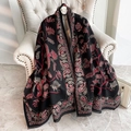 Dettaglio di scialle nero tipo cashmere con motivi paisley rossi e bordi sfrangiati - Nero
