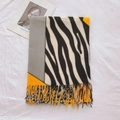 Detailopname van sjaal met zebraprint, kwastjes, oranje en grijze kleuraccenten - Helder Geel