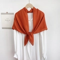 Detail of caramel linen shawl draped over a white shirt with an elegant knot style - Caramel Orange