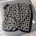 Détail d'une écharpe à motifs géométriques noir et blanc avec bords effilés et étiquette - 130x130cm / Noir