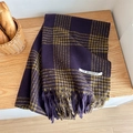 Detail of purple and yellow plaid scarf with fringe tassels on a wooden table - Purple