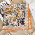 Detailed close-up of a floral silk scarf with orange borders and checkered patterns - Orange