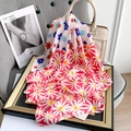 Detail of colorful daisy printed silk scarf draped over a white leather handbag on a chair - Red (70FJ373-3)